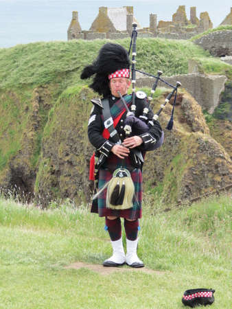 Lone piper in front of Dunnottar Castle, near Stonehaven, Scotlandのeditorial素材