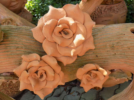 Roses made from terracotta on a terracotta log.の写真素材