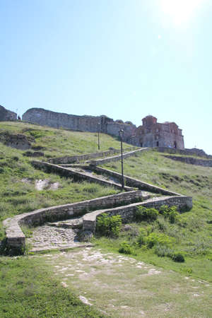 Pathway leading up to an old Albanian church built high on a hillside above a town in the valley below.の写真素材