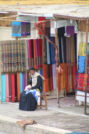 Vendor selling his wares from the market along the banks of the Nile. Customers are from the tourist boats which stop to view the local temple.のeditorial素材