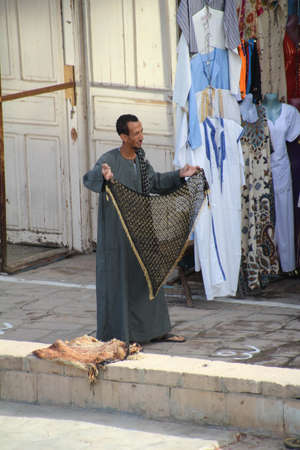 Vendor selling his wares from the market along the banks of the Nile. Customers are from the tourist boats which stop to view the local temple.のeditorial素材