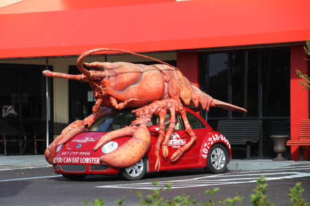 Kissimmee, USA - 13 November, 2019: Giant model lobster mounted on a small car advertising a seafood restaurant in Florida.のeditorial素材