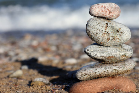 A pile of stones balanced upon one another with a sea wave in the backgroundの写真素材