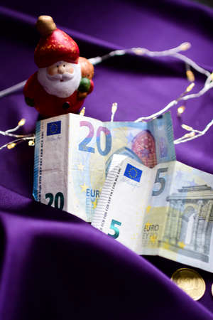 Christmas decoration with euro banknotes and Santa Claus on a purple backgroundの写真素材