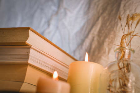 A stack of books, candles and dried flowers on a light backgroundの写真素材