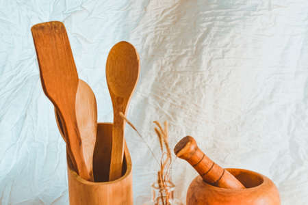Wooden kitchen utensils and mortar on white fabric background.の写真素材