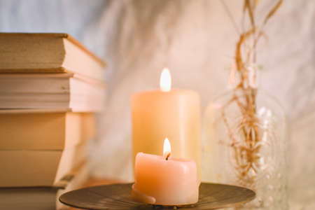 Burning candles and books on a wooden stand. Selective focus.の写真素材