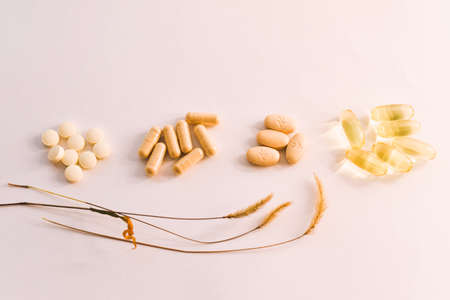 Alternative medicine and healthy lifestyle concept. Pills, capsules and oat grains on white background.の写真素材