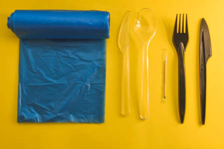 Flat lay composition with plastic garbage bags and cutlery on yellow backgroundの写真素材