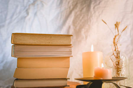 Stack of books, candles and dry grass on a wooden table.の写真素材
