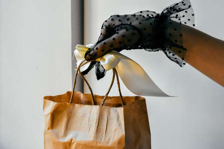 Close-up of the hand of a woman holding a paper shopping bag.の写真素材