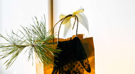 Christmas gift bag with ribbon and bow on the background of the Christmas treeの写真素材