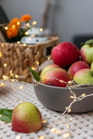 Apples in a bowl on the table with garland lights.の写真素材