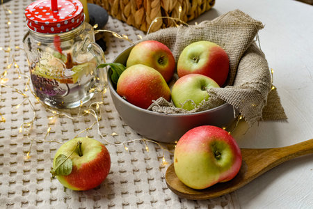Apples in bowl and bottle of water on wooden table with garlandの写真素材
