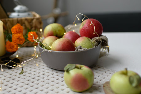 Ripe apples in a bowl on a table with a garlandの写真素材