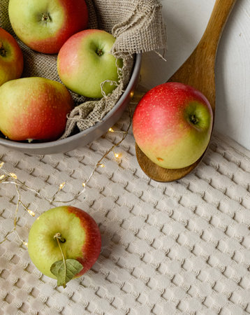 Red and green apples in a bowl on a white wooden background.の写真素材
