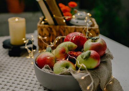Wicker basket with apples, candles and garland on the tableの写真素材