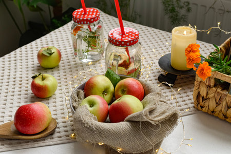 Apples in a bowl on the table with a glass jar of waterの写真素材