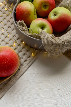 Apples in a bowl with garland on white wooden background.の写真素材