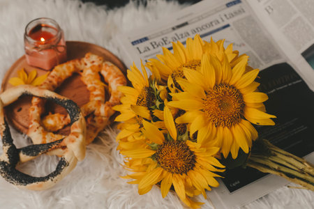 Bouquet of sunflowers, pretzels and a candle on a white carpet.の写真素材
