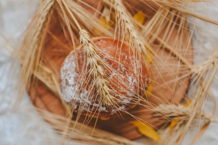 Ears of wheat and bread on a wooden plate. Selective focus.
