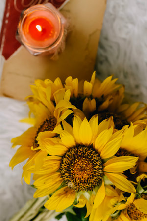 Bouquet of yellow sunflowers with a book and a candleの写真素材