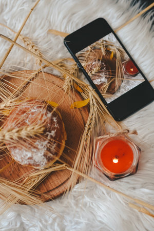 A bouquet of wheat, bread and a burning candle on a white backgroundの写真素材