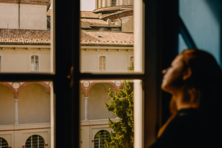 Woman looking out the window in Prague, Czech Republicの写真素材