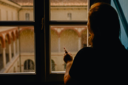 Young woman looking through the window at the mosque in the rain.の写真素材