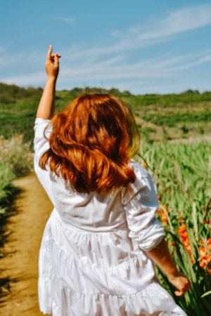 Red-haired girl in a white dress in a field of poppiesの写真素材