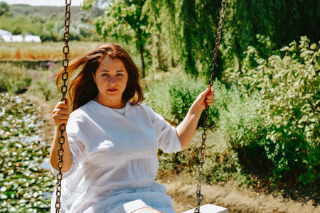 Portrait of a beautiful woman on a swing in the park.の写真素材