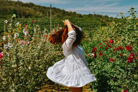 Beautiful girl in white dress dancing in the field of flowers.の写真素材