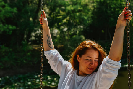 Portrait of a red-haired girl in a white T-shirt on a swing