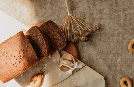 Bread, bagels, garlic and ears of wheat on sackcloth backgroundの写真素材