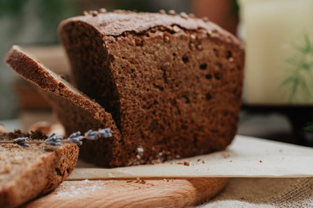 Sliced rye bread on cutting board with lavender and flourの写真素材
