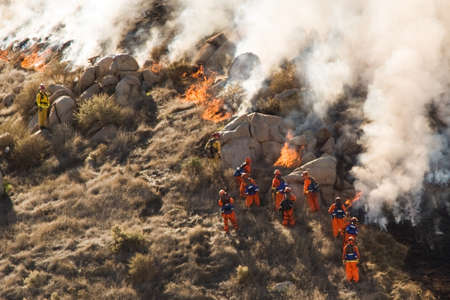 Firefighters fight brushfire on rocky hillside.のeditorial素材