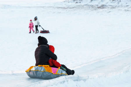 Cheerful people walks in the park in winter. Their rolls down the hills.の写真素材