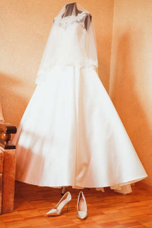 A wedding dress on a mannequin and shoes are next on the floorの写真素材