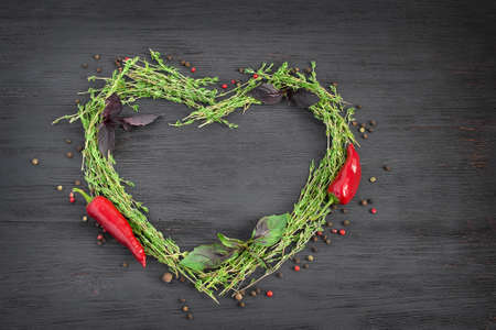 Fresh thyme herbs and spices laid out in a heart shape on a dark backgroundの写真素材