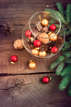 Christmas composition with Christmas balls, nuts, fir cones and twigs on a wooden backgroundの写真素材