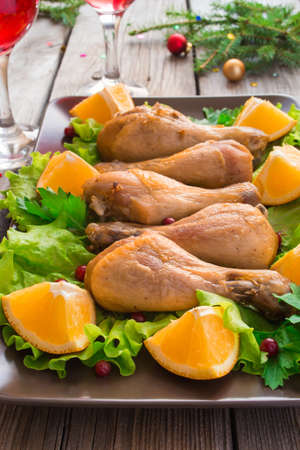 Fried chicken legs with lettuce and oranges on a plate close-up.の写真素材