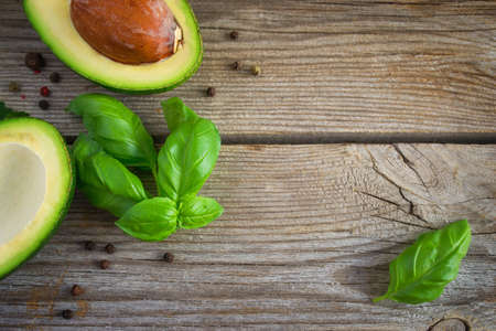 Food background with avocado and basil on old wooden boards. Top view, space for text.