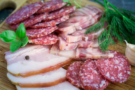 Slices of bacon, salami and fresh herbs, selective focus.の写真素材