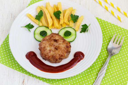 Funny food face with a chop, French fries and cucumber.の写真素材