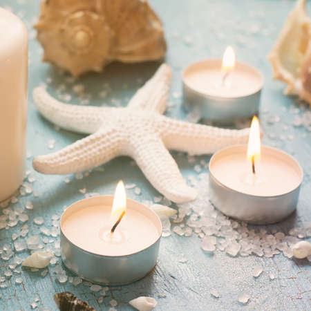 Burning candles and starfish on a blue background, tinted.の写真素材