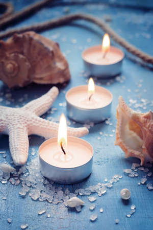 Three burning candles in a row on background of sea objects, tintedの写真素材