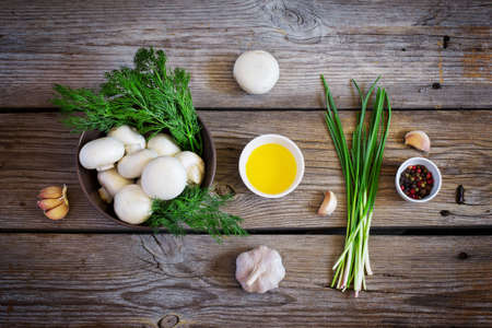 Bowls with mushrooms champignons, herbs and spices on the old wooden background, rustic style, top viewの写真素材
