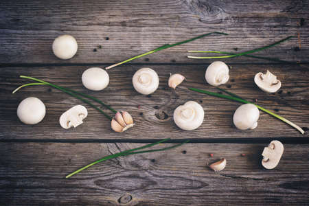 Champignon mushrooms, peppercorns and herbs on an old wooden background, tintedの写真素材