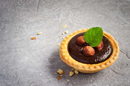 Small Chocolate Tart with almonds on a gray stone background, space for textの写真素材