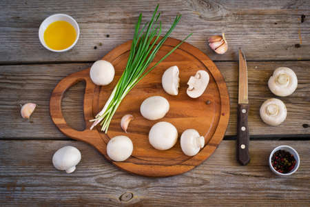 Champignon mushrooms and herbs on a cutting board,  top view, tintedの写真素材